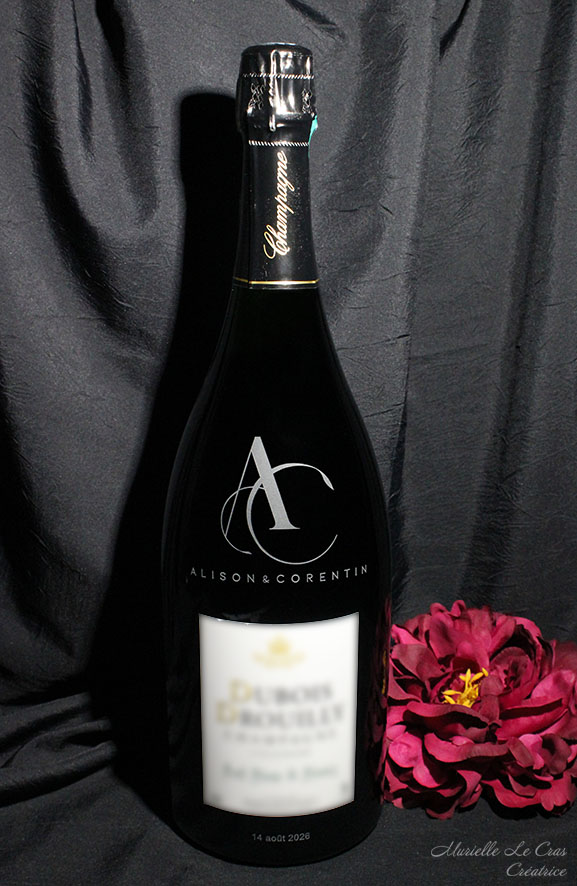 Bouteille de champagne personnalisée pour un cadeau de mariage avec les initiales entrelacées et les prénoms des mariés.